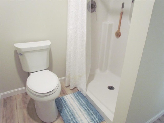 bathroom with hardwood / wood-style flooring, toilet, and a shower with curtain