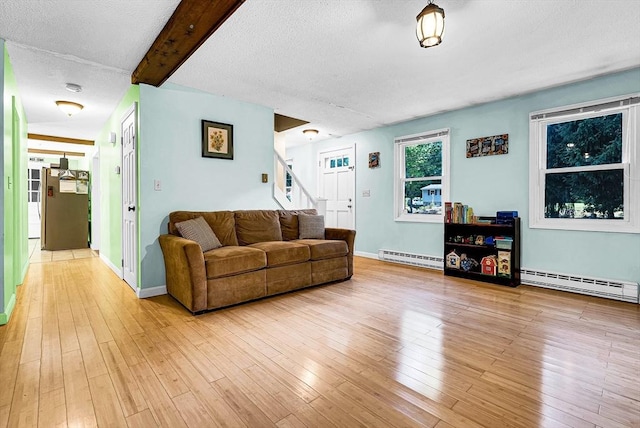 living area featuring stairs, light wood-type flooring, beamed ceiling, and a baseboard radiator