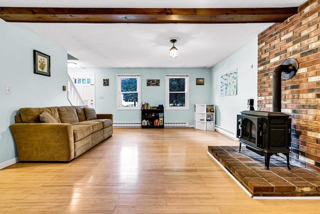 living room with a textured ceiling, baseboard heating, light wood-type flooring, beam ceiling, and a wood stove