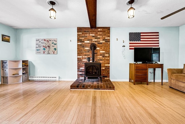 living area with a baseboard radiator, wood finished floors, baseboards, beamed ceiling, and a wood stove