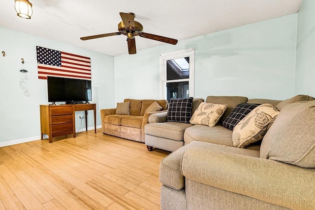 living room featuring light wood-type flooring, ceiling fan, a textured ceiling, and baseboards