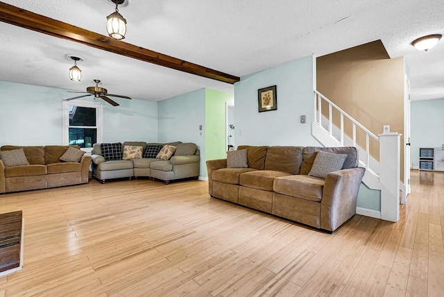 living room with light wood-style flooring, a textured ceiling, stairway, and beamed ceiling