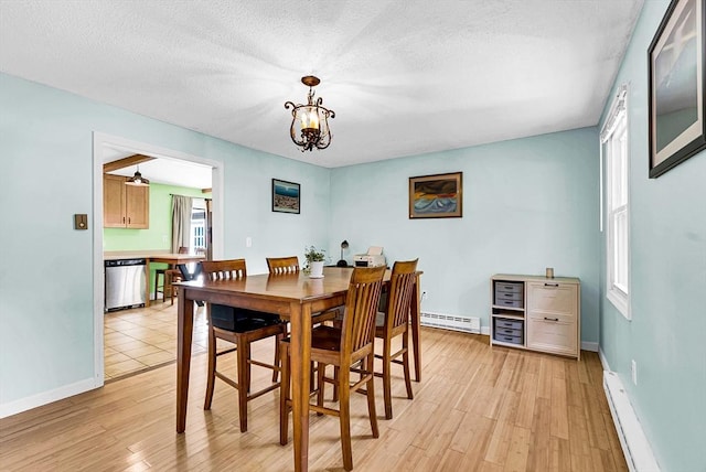 dining room featuring a baseboard radiator, baseboard heating, light wood-style floors, a textured ceiling, and baseboards