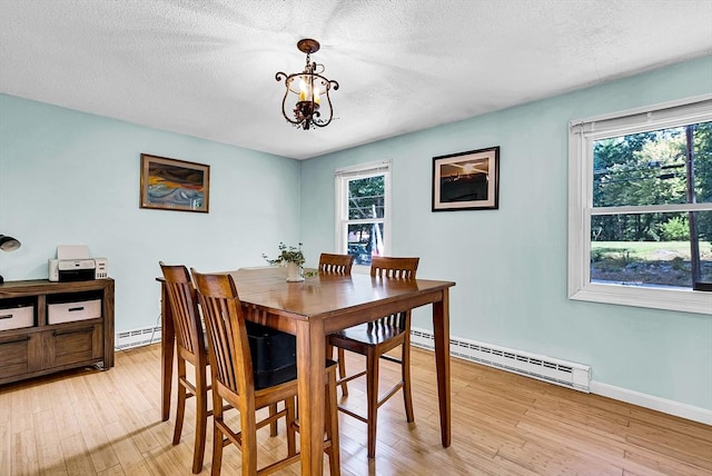 dining space with a textured ceiling, a baseboard radiator, a notable chandelier, a baseboard heating unit, and light wood-type flooring