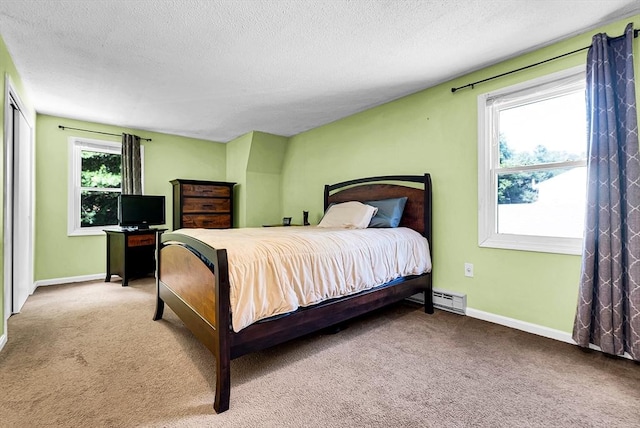 carpeted bedroom with a textured ceiling, baseboard heating, and baseboards