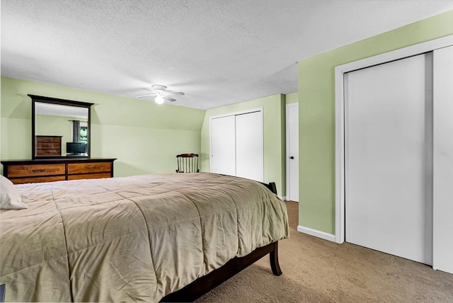 carpeted bedroom featuring lofted ceiling, ceiling fan, a textured ceiling, and two closets