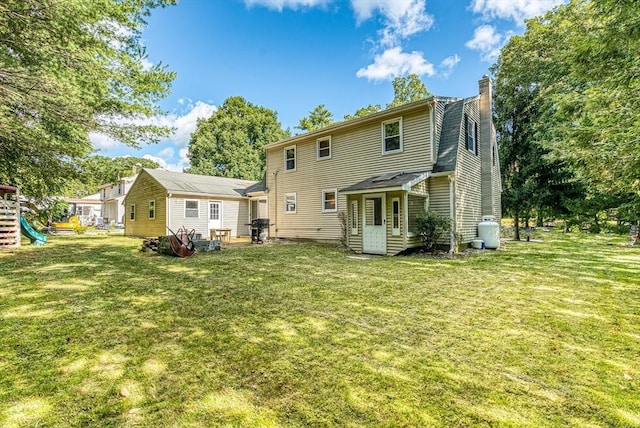 rear view of property with a yard, a chimney, and a playground