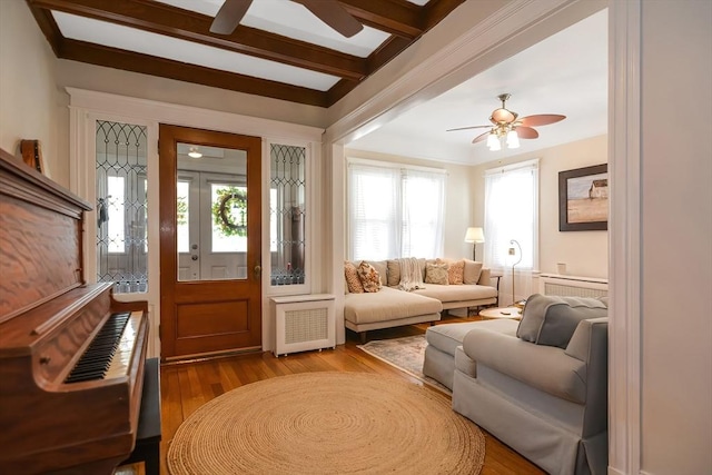 interior space with light hardwood / wood-style floors, radiator heating unit, a healthy amount of sunlight, and beam ceiling