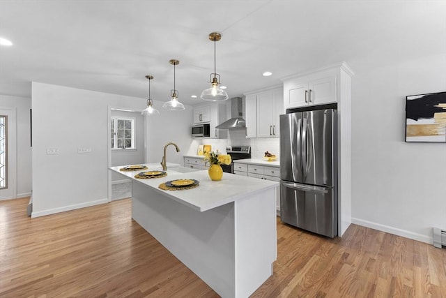 kitchen with stainless steel appliances, wall chimney exhaust hood, light wood-type flooring, and a sink