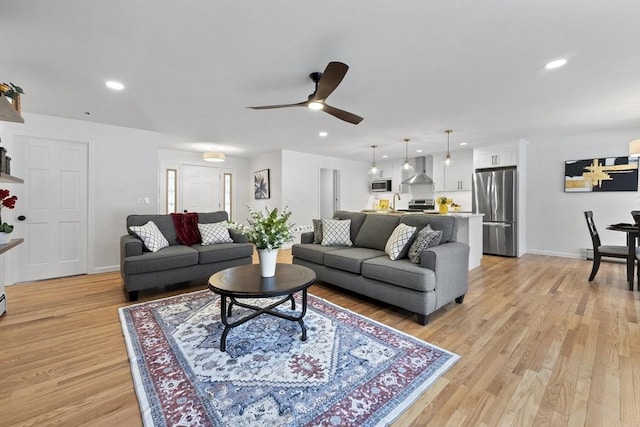 living area featuring baseboards, ceiling fan, light wood finished floors, and recessed lighting