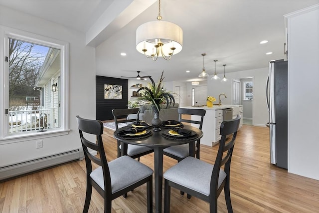 dining area featuring light wood finished floors, ceiling fan with notable chandelier, baseboard heating, and recessed lighting