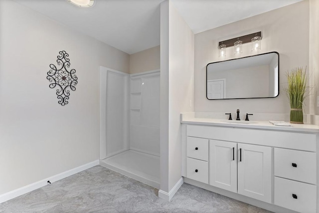 bathroom with a stall shower, baseboards, and vanity