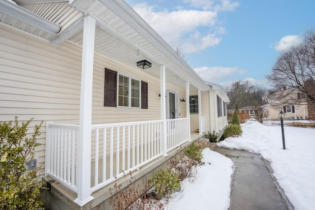 snow covered property entrance with covered porch