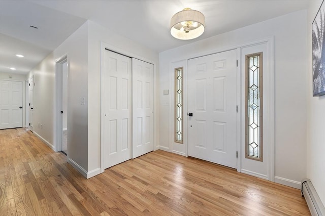 foyer with baseboards, a baseboard radiator, and light wood-style floors