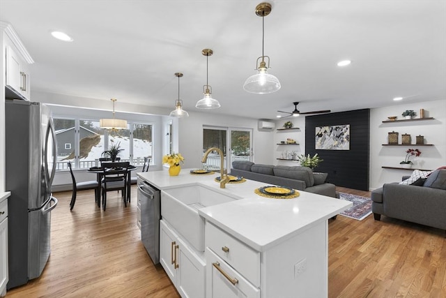 kitchen featuring appliances with stainless steel finishes, open floor plan, light countertops, light wood-style floors, and a sink