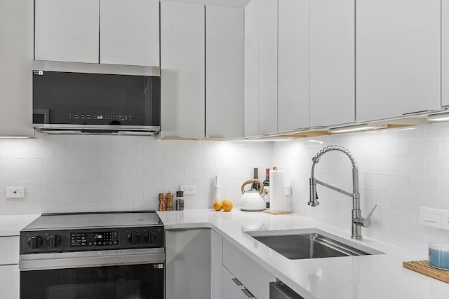 kitchen featuring stainless steel microwave, light countertops, electric range, decorative backsplash, and a sink