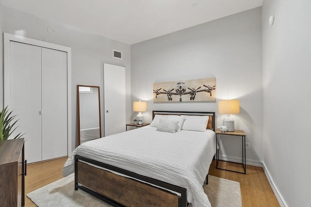 bedroom with visible vents, a closet, baseboards, and wood finished floors