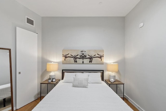 bedroom with wood finished floors, baseboards, and visible vents