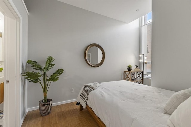 bedroom featuring wood finished floors, baseboards, and multiple windows