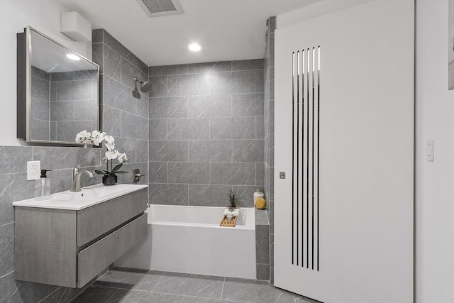 bathroom featuring washtub / shower combination, vanity, recessed lighting, visible vents, and tile walls
