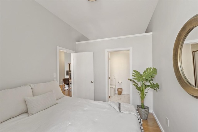 bedroom with light wood-style flooring, baseboards, connected bathroom, and vaulted ceiling