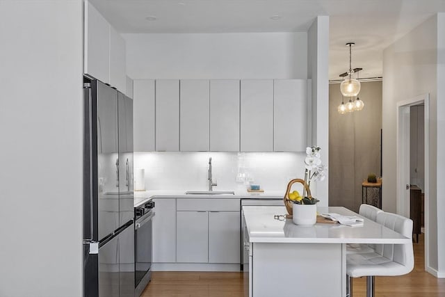 kitchen with a sink, light wood-style floors, decorative backsplash, range, and a breakfast bar area