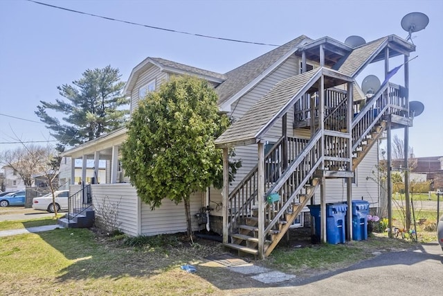 view of property exterior featuring a shingled roof and stairway