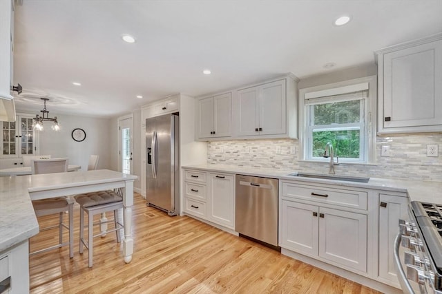 277 Ridgewood Dr, Norwood, MA 02062 - kitchen with stainless steel appliances, tasteful backsplash, light wood-style flooring, a kitchen breakfast bar, and white cabinets