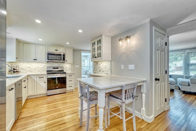 277 Ridgewood Dr, Norwood, MA 02062 - kitchen with stainless steel appliances, light wood-type flooring, decorative backsplash, glass insert cabinets, and recessed lighting