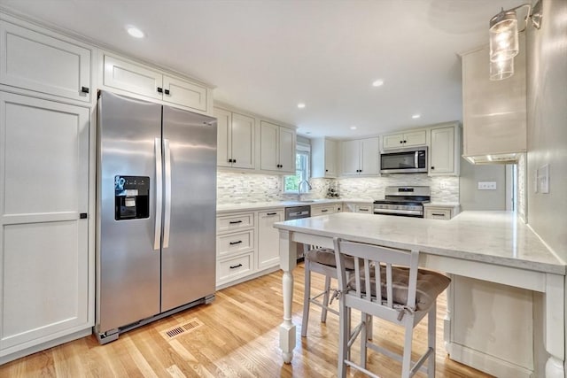 277 Ridgewood Dr, Norwood, MA 02062 - kitchen with stainless steel appliances, light wood-style flooring, a peninsula, tasteful backsplash, and recessed lighting