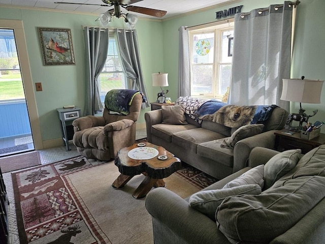 living area with crown molding, ceiling fan, and a wealth of natural light