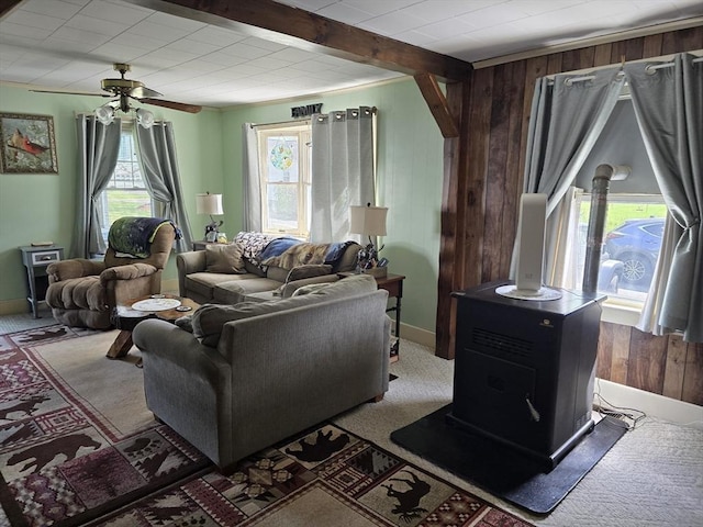 living area with wooden walls, a ceiling fan, a wood stove, and light colored carpet