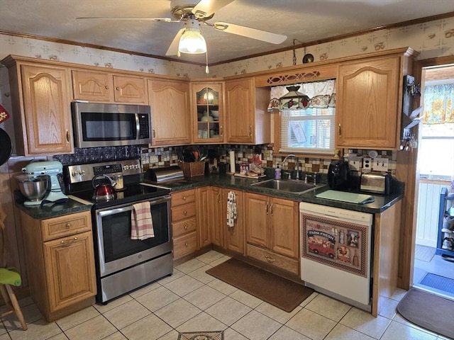 kitchen with dark countertops, ceiling fan, a sink, stainless steel appliances, and decorative backsplash