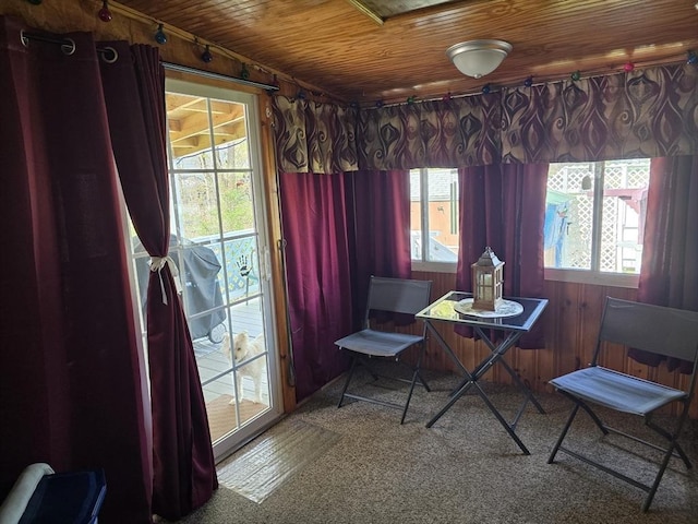 carpeted dining area with wooden walls and wood ceiling