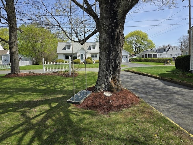 view of yard with aphalt driveway, fence, a residential view, and a garage