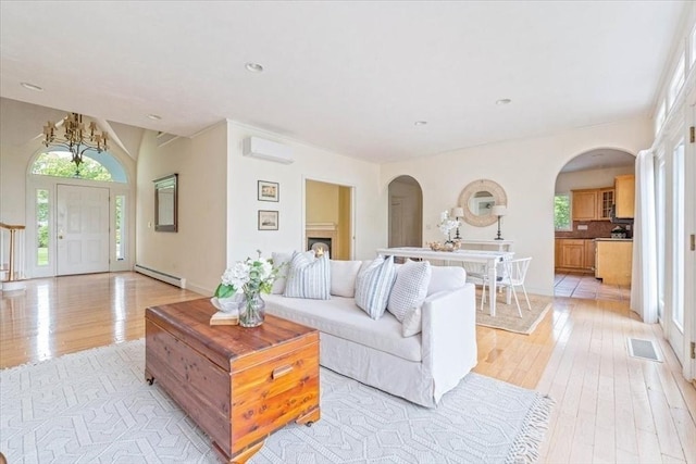 89 Standish Rd, Bourne, MA 02562 - living area featuring a baseboard radiator, an AC wall unit, light wood finished floors, arched walkways, and recessed lighting