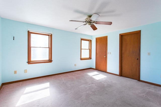 unfurnished bedroom with carpet, a ceiling fan, baseboards, and multiple windows