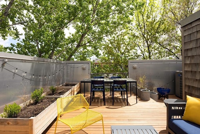 wooden deck featuring a garden, fence, and outdoor dining space