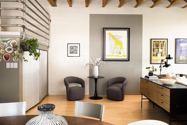 living area featuring wood finished floors, beam ceiling, and baseboards