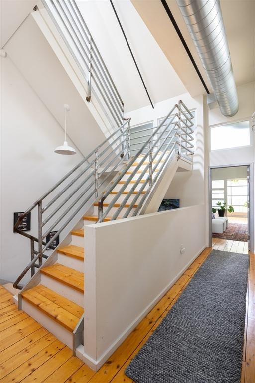 stairway with wood-type flooring and a towering ceiling