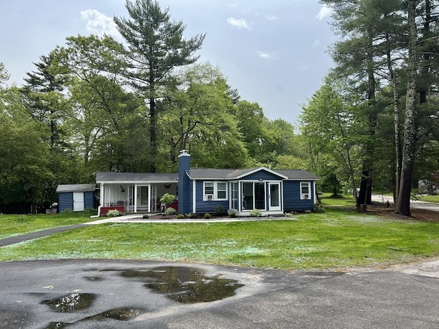 view of front of property with a chimney, an outbuilding, and a front yard