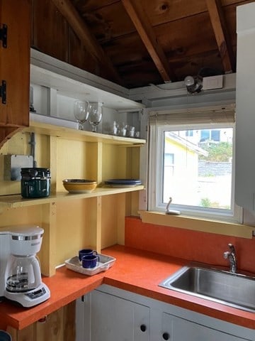 kitchen featuring wooden ceiling, sink, vaulted ceiling with beams, and white cabinets