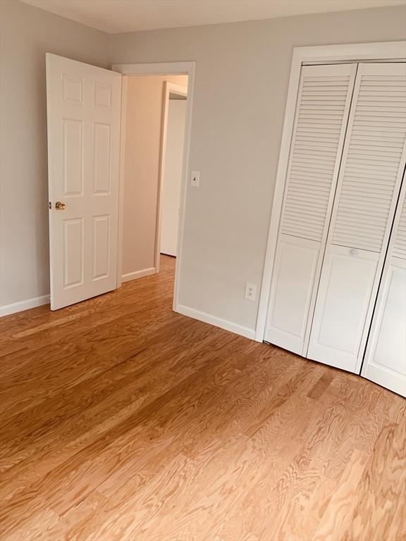 5 Woodsum Dr Unit 7, Braintree, MA 02184 - unfurnished bedroom with light wood-style flooring, baseboards, and a closet
