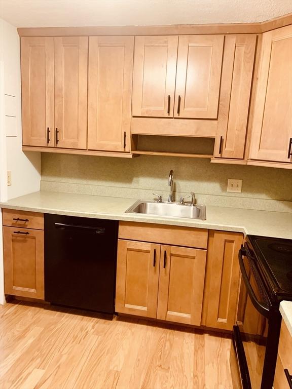 5 Woodsum Dr Unit 7, Braintree, MA 02184 - kitchen with black appliances, a sink, light countertops, and light wood-style flooring