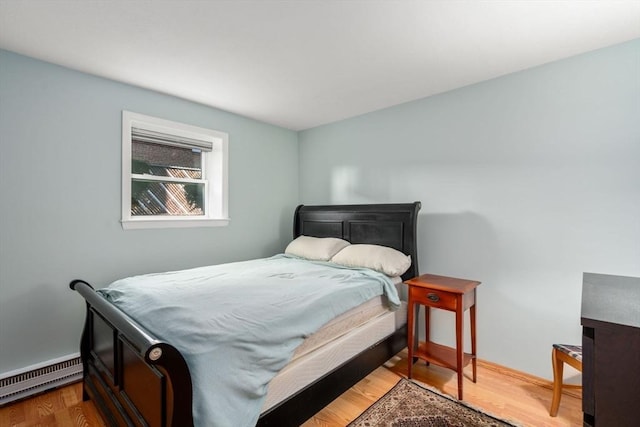 bedroom with baseboard heating, baseboards, and wood finished floors