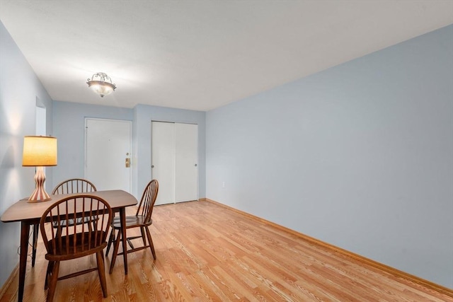 dining space featuring light wood-style flooring and baseboards