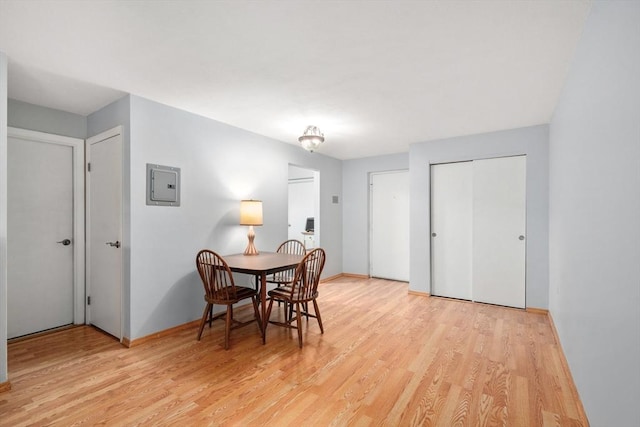 dining space featuring electric panel, baseboards, and light wood-style flooring