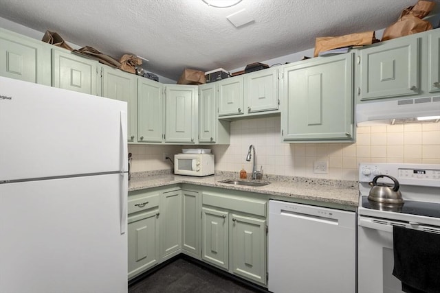 kitchen with backsplash, under cabinet range hood, white appliances, a textured ceiling, and a sink