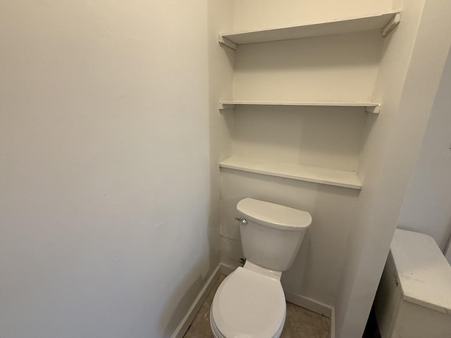 bathroom with baseboards and toilet