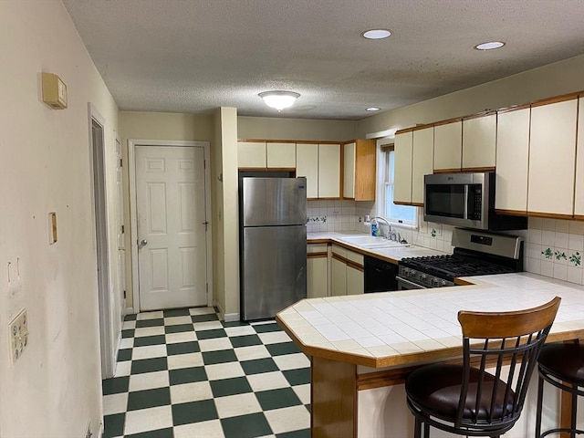 14 Plain Rd E Unit B, Deerfield, MA 01373 - kitchen featuring stainless steel appliances, light flooring, tile countertops, a peninsula, and a sink